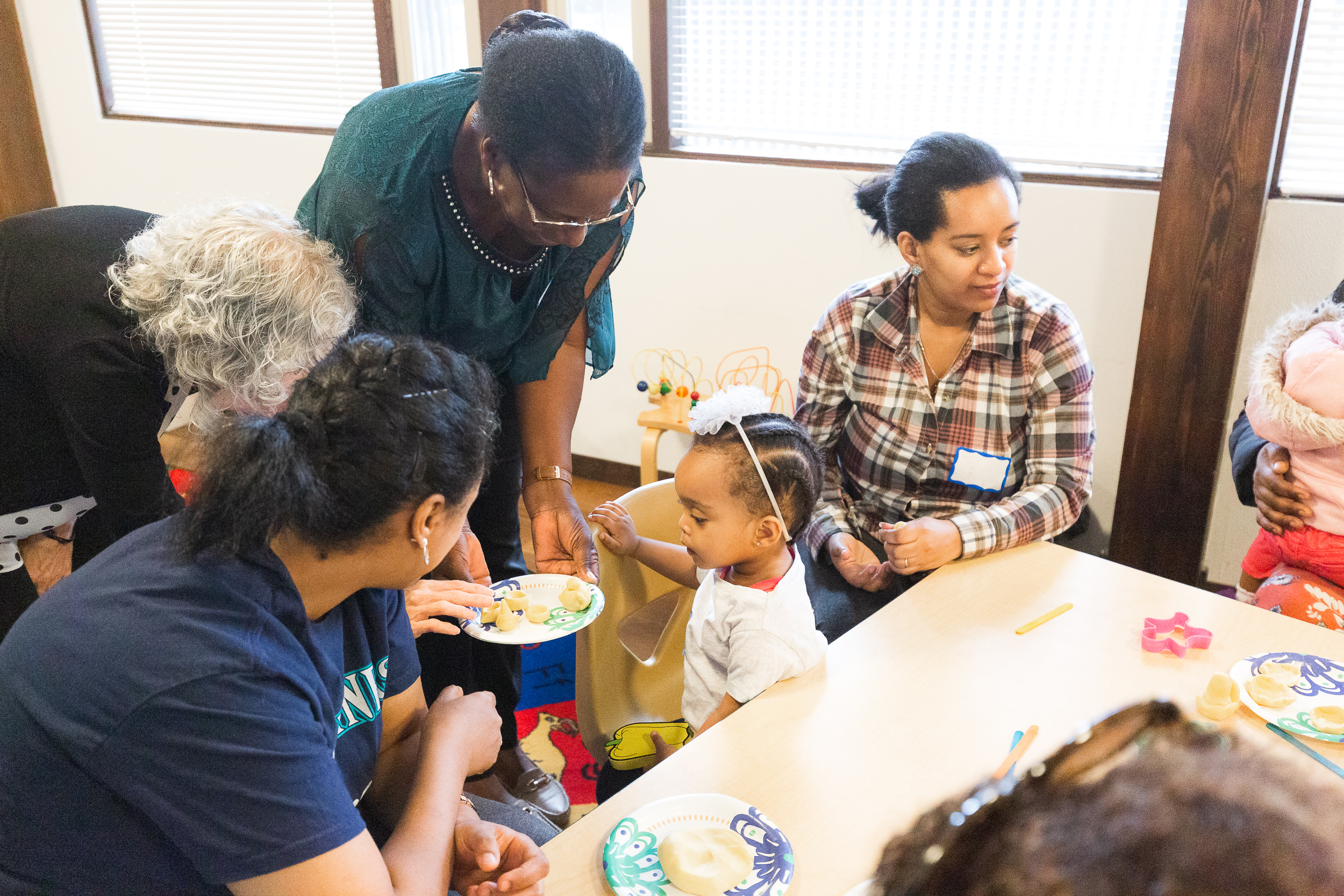 Group of adults attending to a small toddler with toys