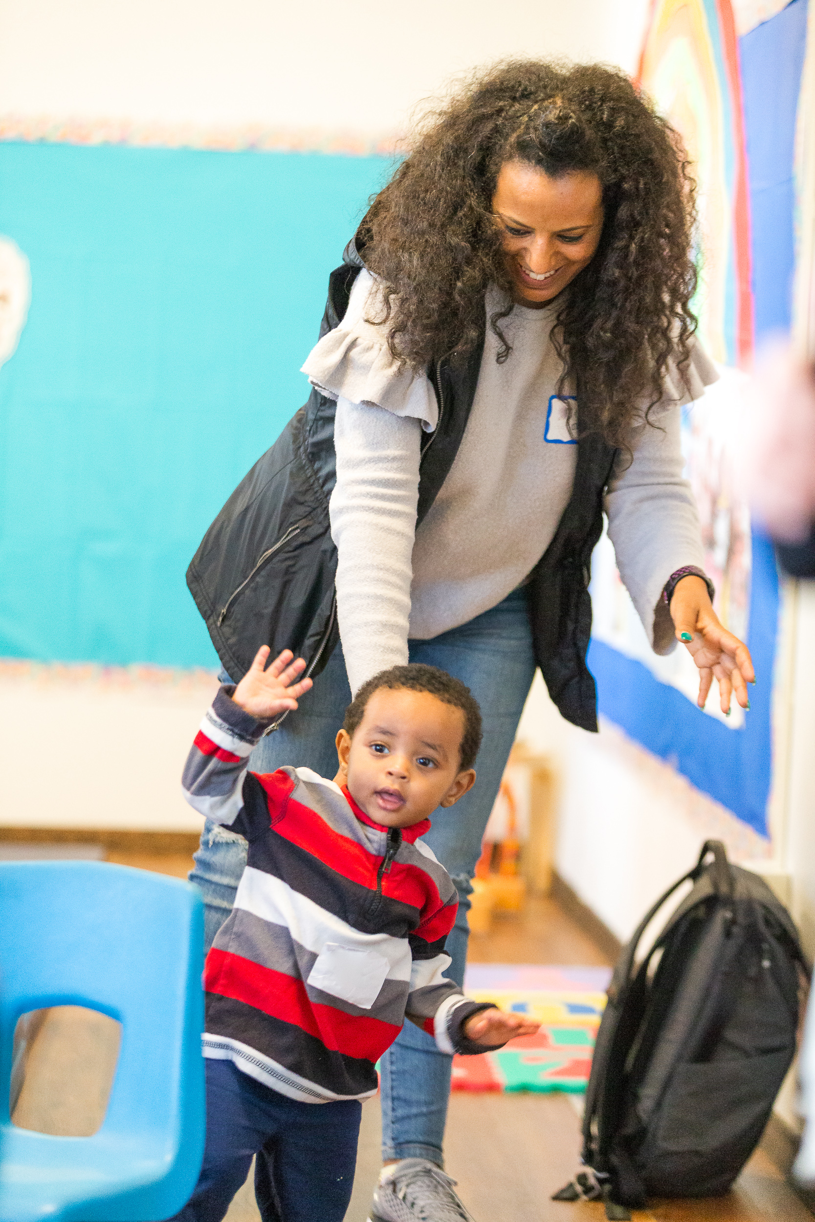 woman standing behind a toddler waving