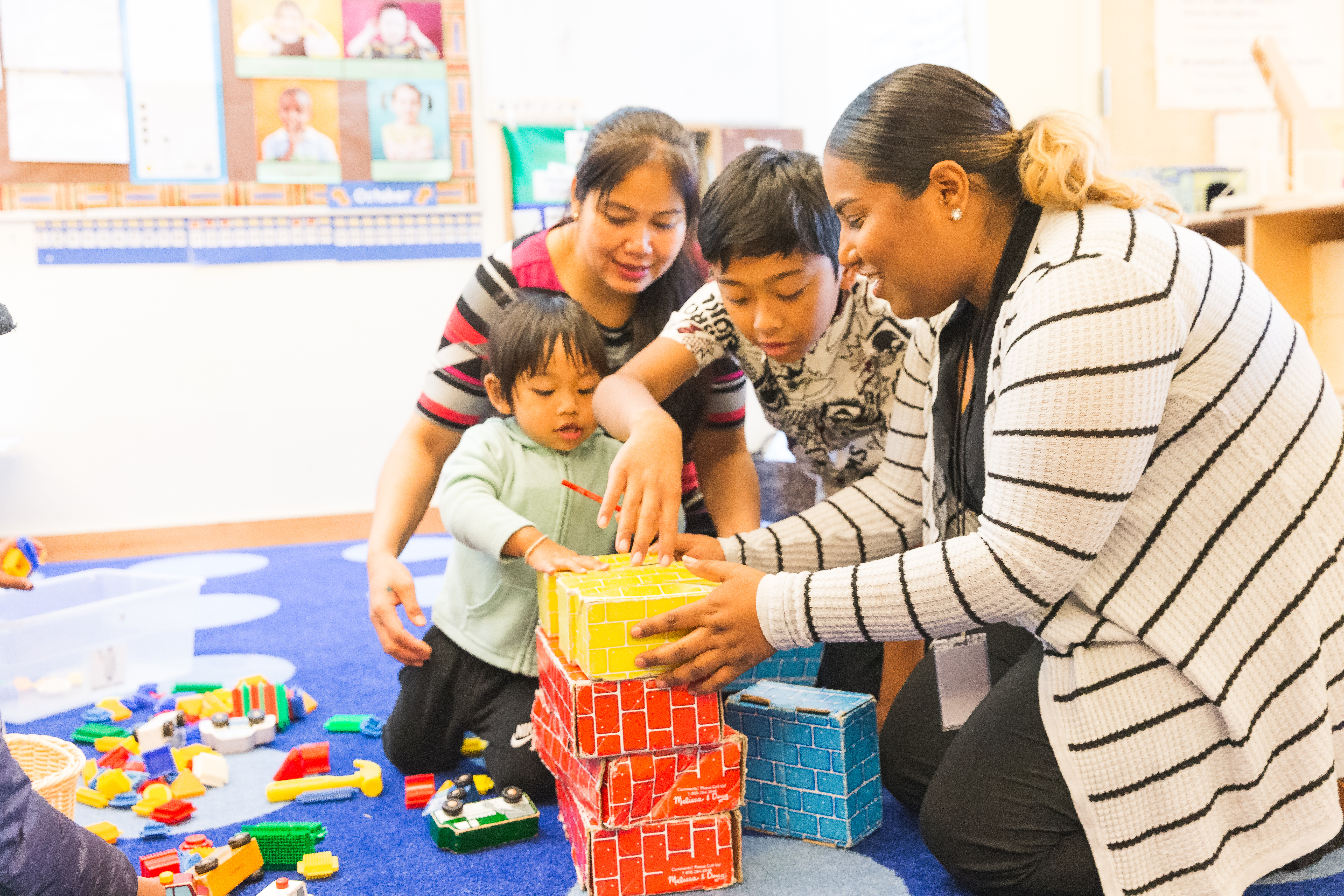 Two women and two children playing with some block toys