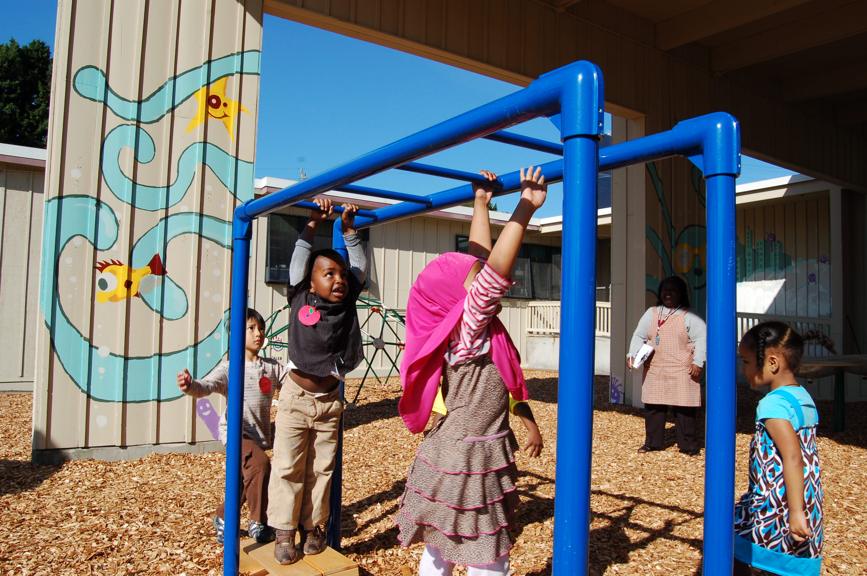 Group of children playing on a set of blue monkey bars
