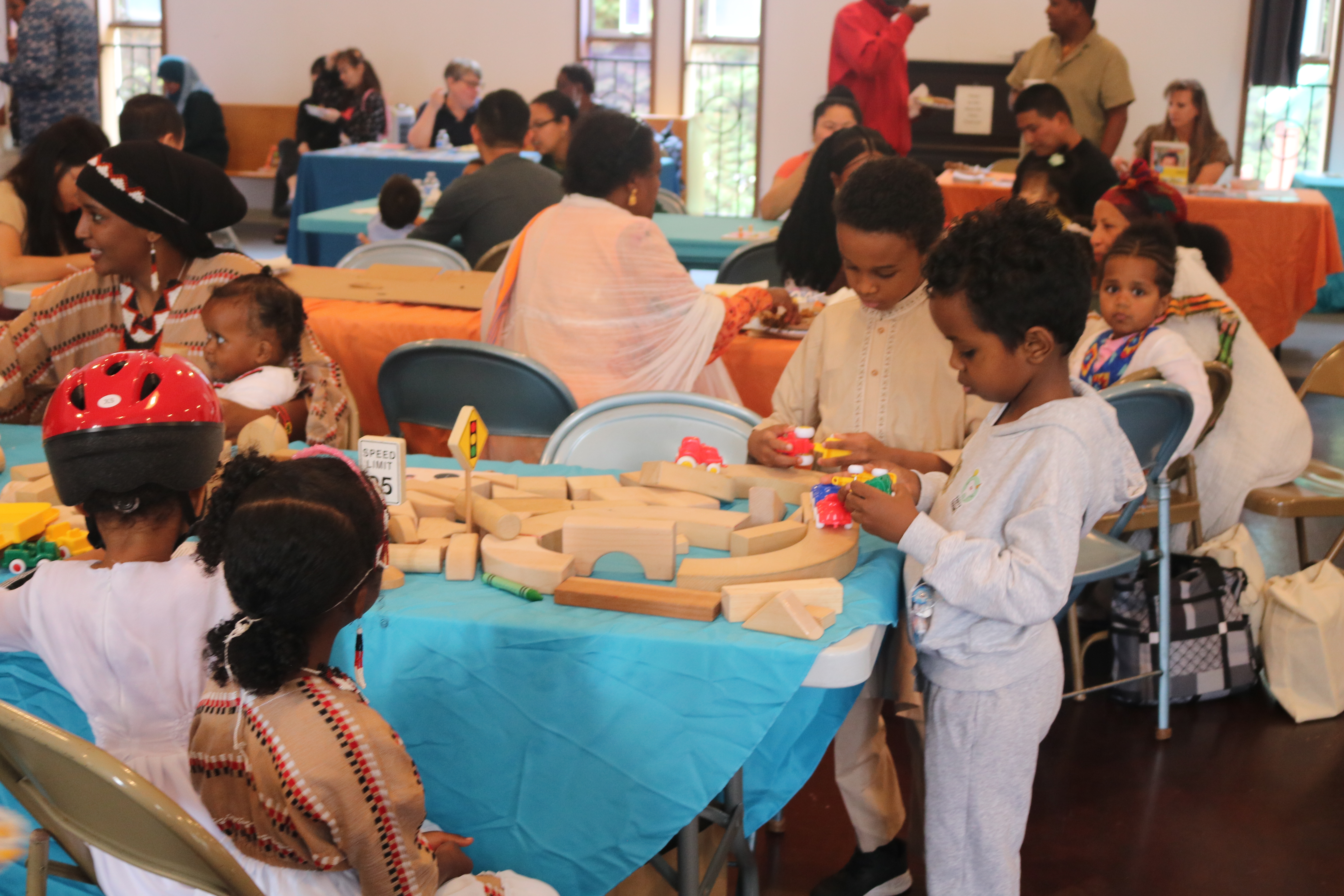 group of kids playing with wooden train track toys at a larger event