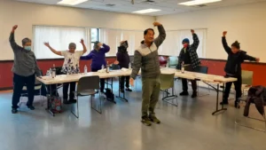 group of people stretching in a room with tables