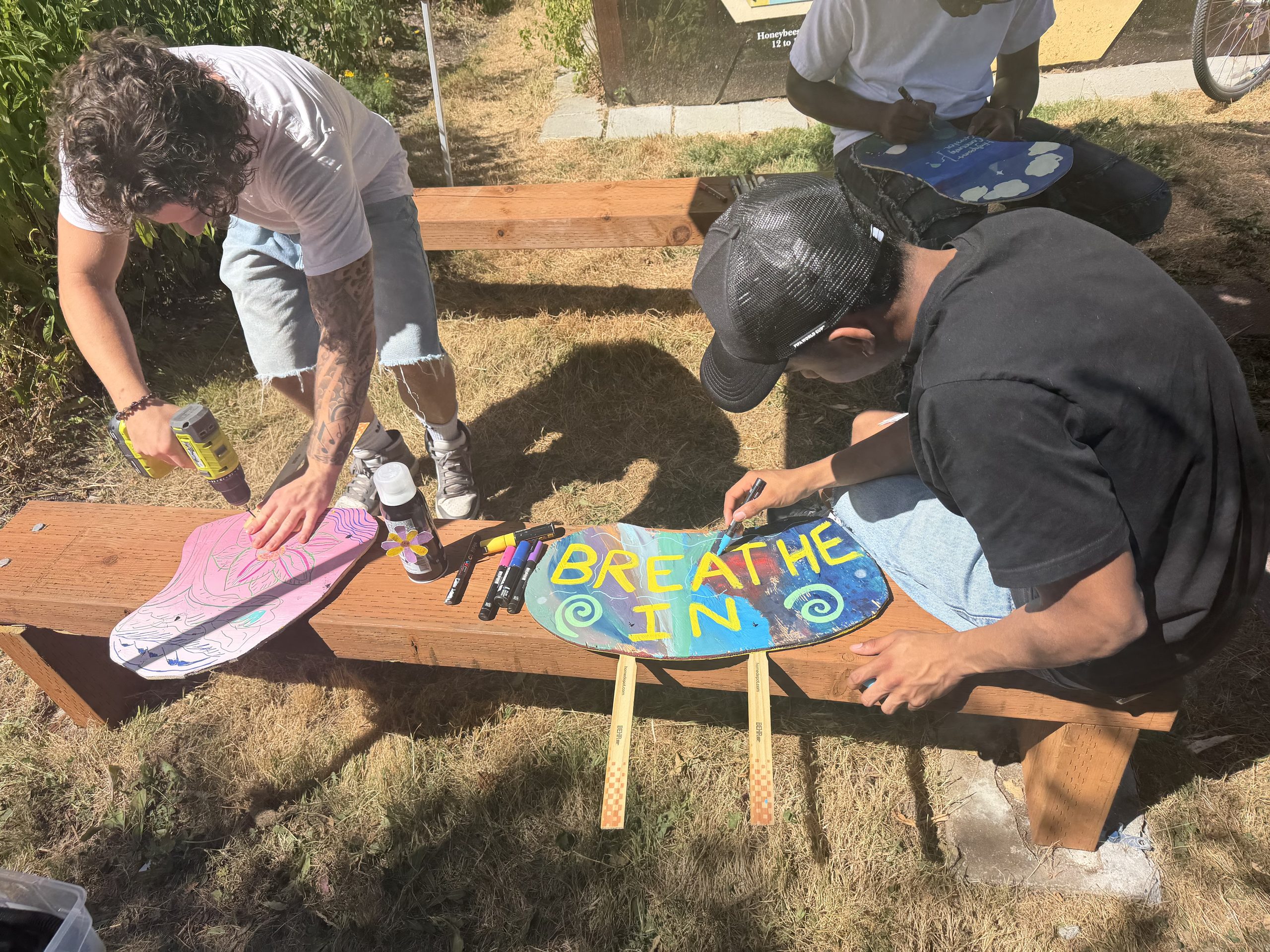 Teenagers painting signs, one that says "breathe in"