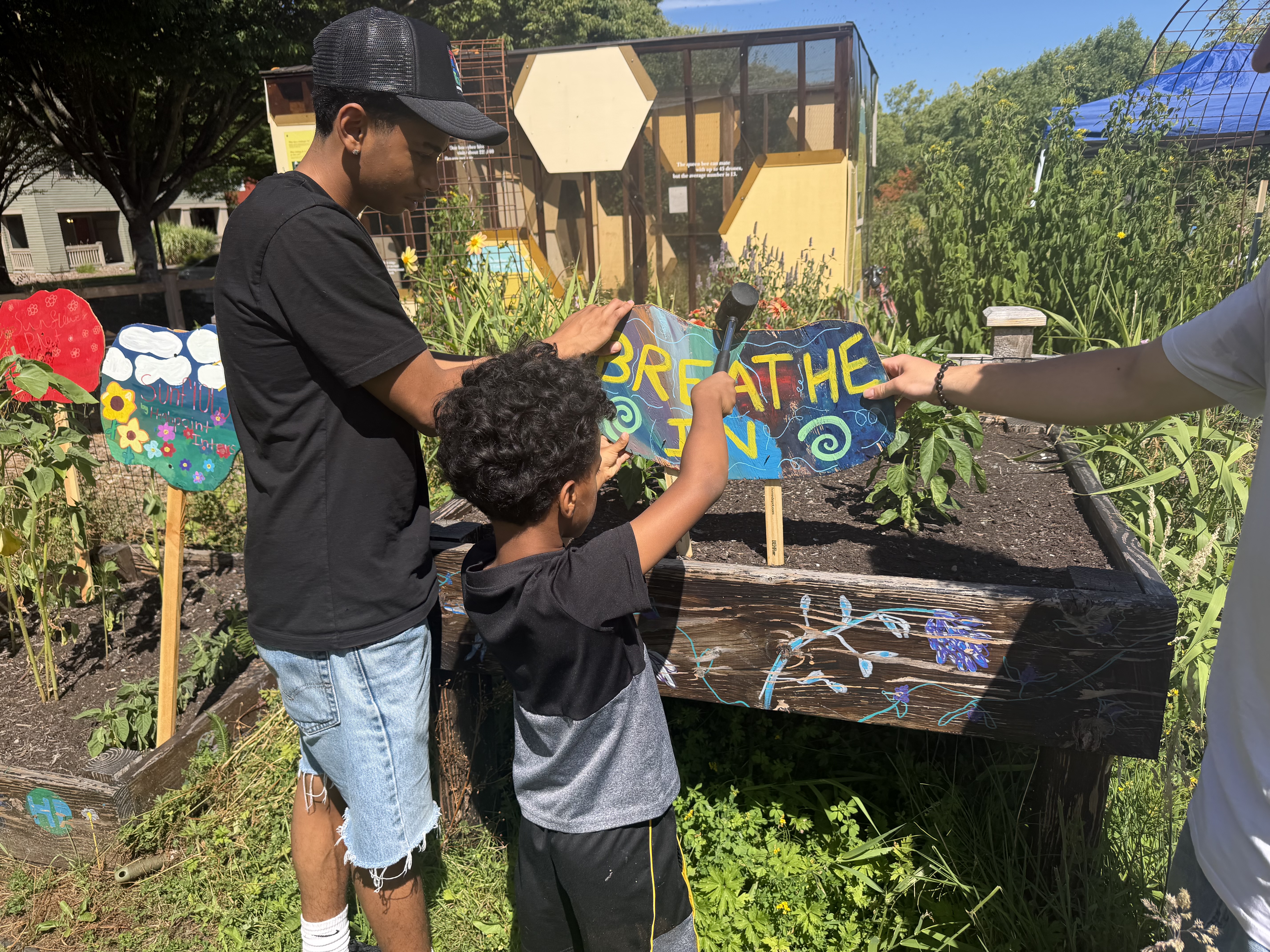 Young child reaching up to put up a sign next to a young adult.